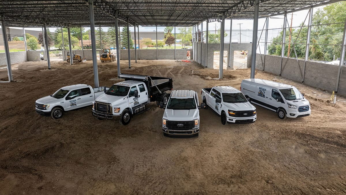 A fleet of Ford commercial vehicles parked at a job site.